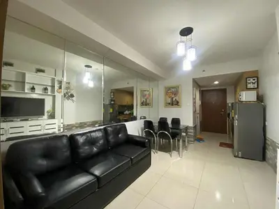 a living room with a black leather couch and a kitchen at Shell Residences Mall of asia Pham in Manila