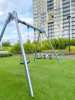 a swing set in a park with buildings in the background at One br cozy resort style condo sunset view balcony Robinson Las Pinas in Manila