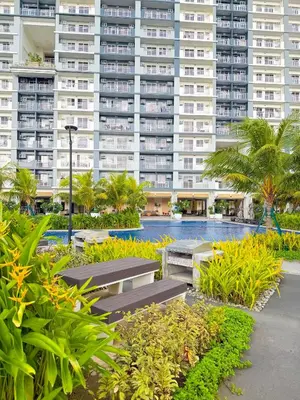 a large apartment building with benches and palm trees at One br cozy resort style condo sunset view balcony Robinson Las Pinas in Manila