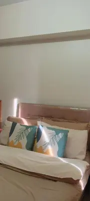 a bed with four pillows on top of it at One br cozy resort style condo sunset view balcony Robinson Las Pinas in Manila