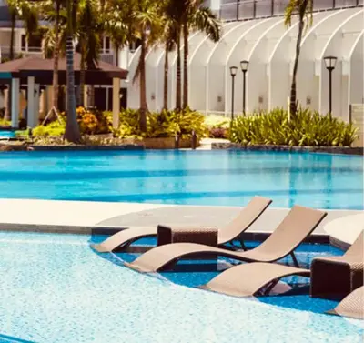 a swimming pool with lounge chairs in a hotel at Comfy Stays in Shell Residences by OneGuestPlace in Manila
