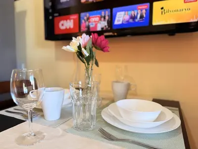 a table with plates and glasses and a vase of flowers at Comfy Stays in Shell Residences by OneGuestPlace in Manila