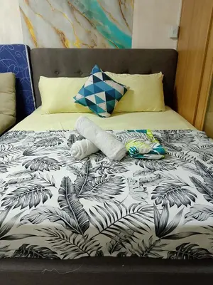 a bed with a black and white comforter and pillows at 1648 b 3beds big cut moa view in Manila
