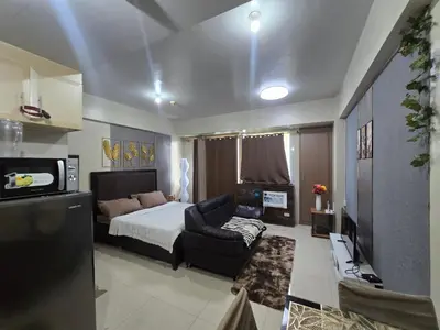 a bedroom with a bed and a couch and a television at Newport Staycation in Manila