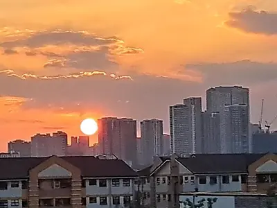 a city skyline with the sun setting behind tall buildings at CORKA Manila in Manila