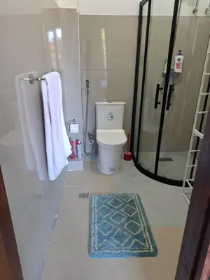 a bathroom with a shower and a toilet and towels at CORKA Manila in Manila
