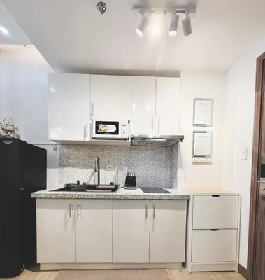 a white kitchen with a sink and a microwave at Cozy and Comfy Retreat with Balcony in Manila