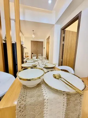 a wooden table with white plates and silverware on it at Cozy and Comfy Retreat with Balcony in Manila