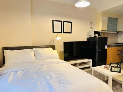 a bedroom with a large bed and a kitchen at 101 Newport Boulevard near NAIA Terminal 3 in Manila