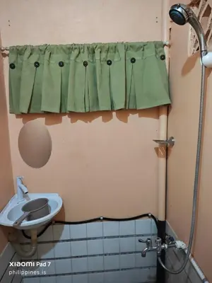 a bathroom with a green shower curtain and a sink at Bunkaroo in Manila