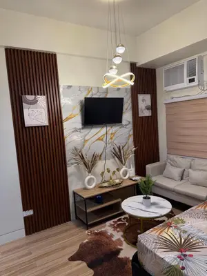 a living room with a couch and a tv on a wall at J&A Cozy Calm Stay in Biñan