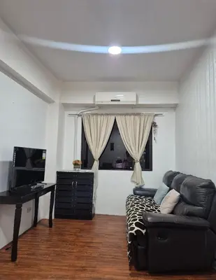 a living room with a black couch and a window at 1BR Retro-styled Condo unit in BGC, Taguig City in Manila