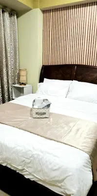 a white bed with a tray on top of it at Cozy Modern Studio Two Palm Tree Villas in Manila