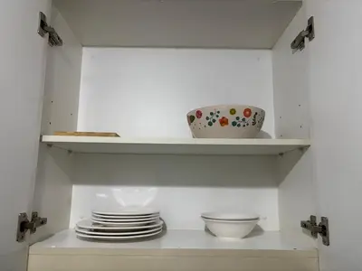 a white shelf with plates and bowls on it at Family Suite-150Newport Boulevard Southwing in Manila