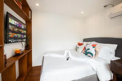 a bedroom with a bed with white sheets and a tv at Container Home Mandaluyong N03 in Manila