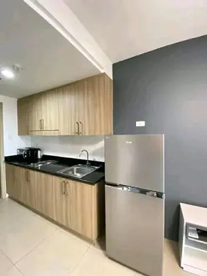 a kitchen with a stainless steel refrigerator and wooden cabinets at Vacation at HM Place in Manila