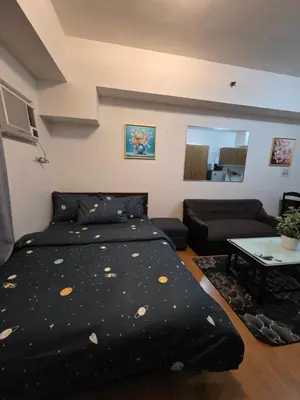 a bedroom with a bed with a black comforter at 8 Adriatico Condominium in Manila