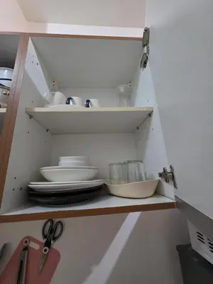 a cabinet with plates and bowls and scissors at 8 Adriatico Condominium in Manila