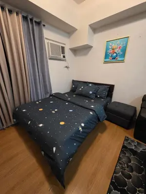 a bedroom with a bed with a blue comforter at 8 Adriatico Condominium in Manila