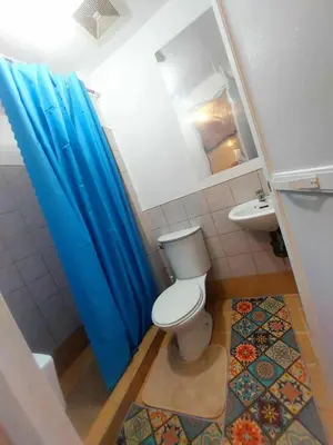 a bathroom with a toilet and a blue shower curtain at Condotels by Mandolin Suite in Manila