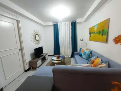a living room with a blue couch and a tv at Condotels by Mandolin Suite in Manila
