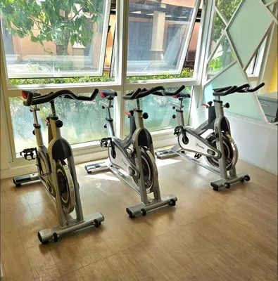 a row of three exercise bikes in a room with windows at J&A Cozy Calm Stay in Biñan