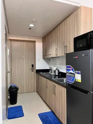 a kitchen with a black refrigerator and wooden cabinets at Apartment in Pasay at Shore Residences in Manila