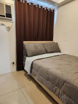 a bedroom with a bed with a brown curtain at Apartment in Pasay at Shore Residences in Manila