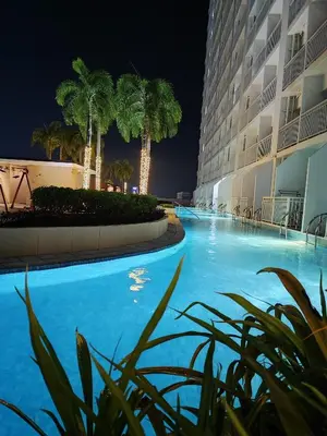 a swimming pool with palm trees in front of a building at ASV Condo Staycation SMDC Breeze in Manila