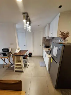 a kitchen with a refrigerator and a table in it at LSB Modern Penthouse in Manila