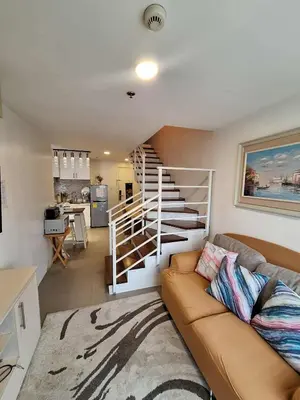 a living room with a couch and a spiral staircase at LSB Modern Penthouse in Manila