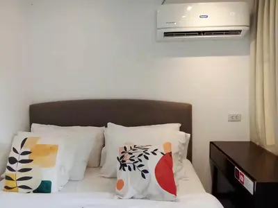 a bedroom with a bed with white pillows and avertisement at Container Home Mandaluyong N04 in Manila