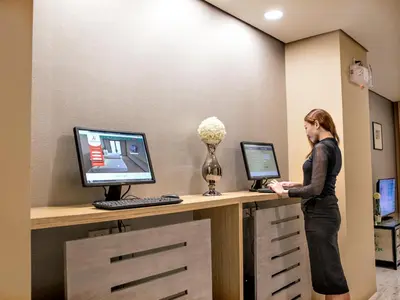 a woman standing at a reception desk with a computer at Jinjiang Inn - Makati in Manila