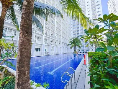 a swimming pool with palm trees and buildings at Manila Bay View Shore1 Residence Tower A in Manila
