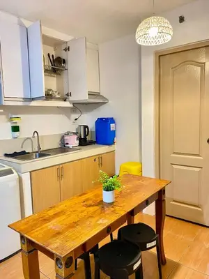 a kitchen with a wooden table and some chairs at Your Comfort Zone Staycation2 in Manila