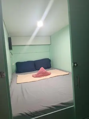 a small room with a bed with a pink towel on it at Uni Capsules in Manila