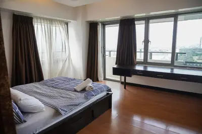 a bedroom with a bed and a desk and windows at Eton Baypark Manila Bay in Manila