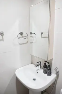a white bathroom with a sink and a mirror at Eton Baypark Manila Bay in Manila