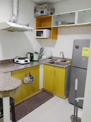 a small kitchen with wooden cabinets and a stainless steel refrigerator at Birch tower condo for renting in Manila