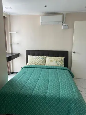 a bed with a green comforter in a bedroom at Robinson's Place Residences, tower 2 in Manila