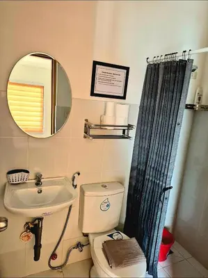 a bathroom with a sink and a toilet and a mirror at Casa Deña Lawa - Cozy Staycation in Calamba in Calamba
