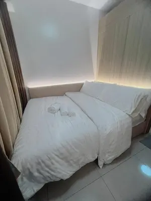 a bed in a small room with white sheets at Affordable Staycation in Pasay near MOA in Manila