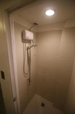 a bathroom with a shower with a light on the ceiling at Quarto Ph in Manila