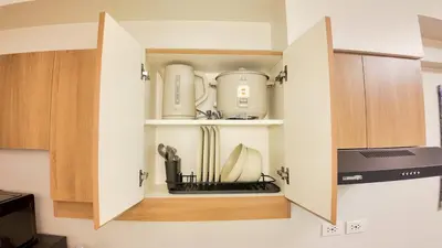 a cupboard filled with appliances in a kitchen at CoZ studio near MAKATI CBD MOA NAIA in Manila