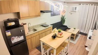 a small kitchen and dining room with a table and refrigerator at CoZ studio near MAKATI CBD MOA NAIA in Manila