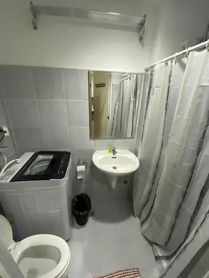 a white bathroom with a toilet and a sink at Sea Residences Dina in Manila