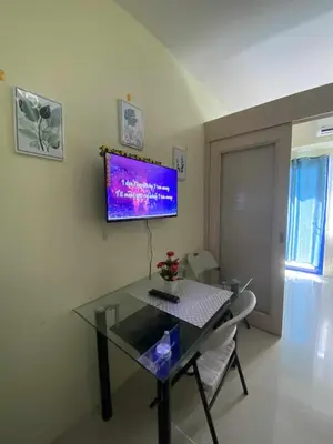 a dining room with a table and a tv on the wall at Sea Residences Dina in Manila