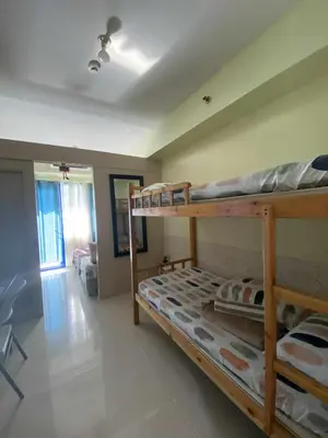 a bedroom with two bunk beds and a living room at Sea Residences Dina in Manila