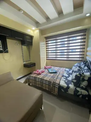 a bedroom with a bed and a couch and a window at 2br Sea Residences pool view dina in Manila