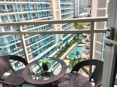 a balcony with chairs and a table and a view of a building at OasisStaycation in Manila